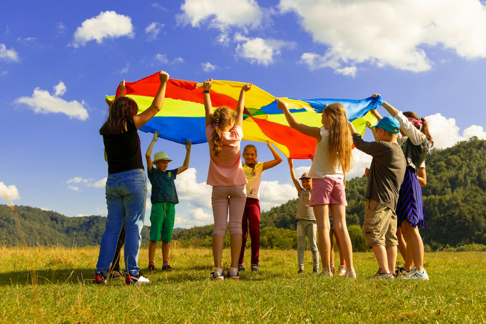 Bambini giocano con un paracadute colorato durante un'attività educativa all'aperto
