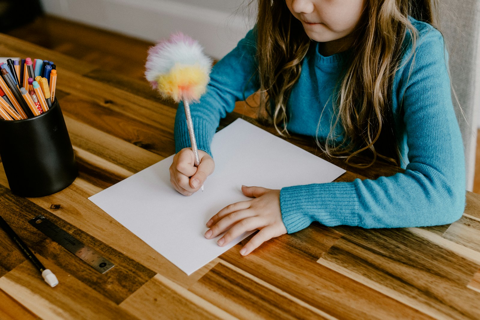 Bambina scrive al tavolo durante un'attività di supporto scolastico